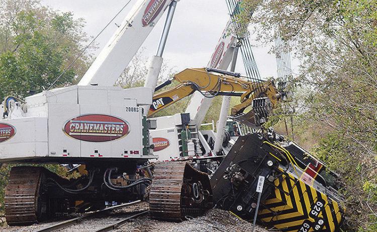 Cranes work Wednesday morning to reset this toppled locomotive on E. Modelle Avenue, behind Bar-S. CDN | Christian Jacobsen