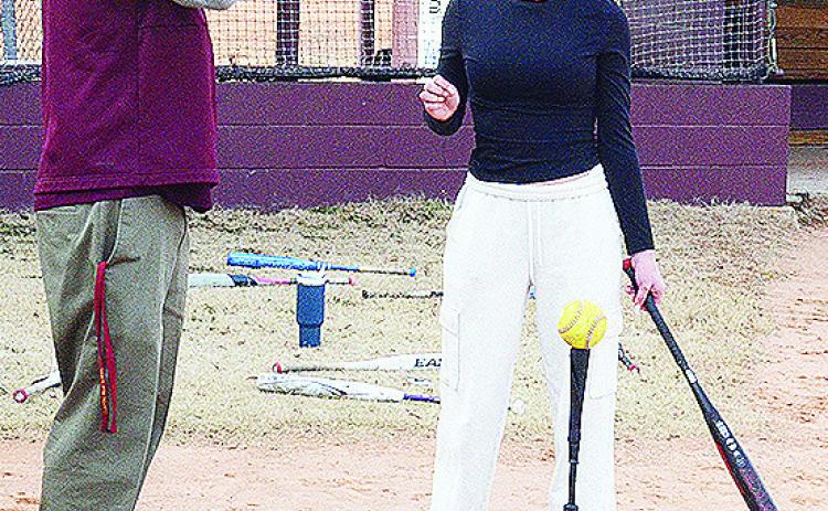 Clinton’s new softball coach Michael Deatherage, left, instructs Reese Giblet through a hitting exercise. CDN | Sam Goodwyn