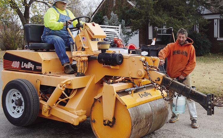Mike Abramson, left, and Timothy Braecklein prepare a road roller to be used while fixing a pothole Wednesday afternoon at the intersection of 10th Street and Broadway Avenue. CDN | Micah Ashcraft