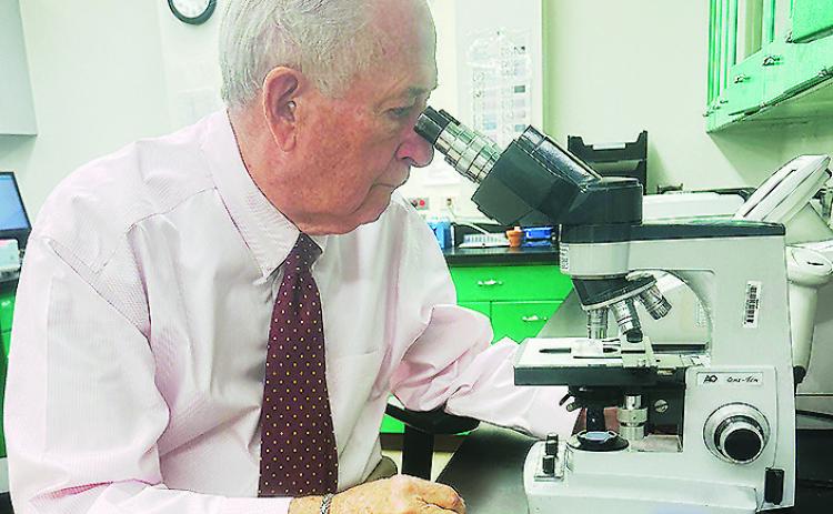 Dr. Raymond Cornelison examines a slide through a microscope in the Clinton Regional Hospital’s lab. CDN | Shiann Dawson