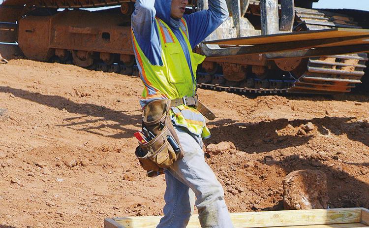 Antonio Garnica carries the next panel to create a box frame for a future concrete support beam Wednesday during construction on Red Wheat Drive. CDN | Christian Jacobsen