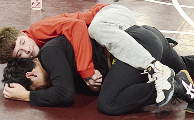 Clinton’s Marcelo Juarez, top, wraps himself around teammate Jackson Brown during practice. CDN | Sam Goodwyn