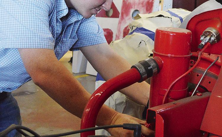 Ethan Hyers checks his students’ work on a tractor project at the Clinton High School Ag Shop. CDN | Micah Ashcraft