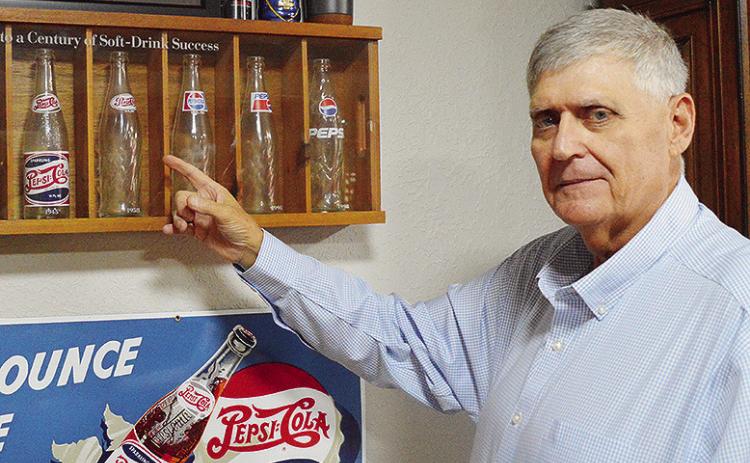 Clinton Chamber of Commerce Chair Mark Nicholson shows off his Pepsithemed glasses and memorabilia in his office at the Pepsi Bottling Group. CDN | Micah Ashcraft