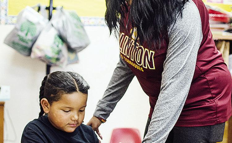 Khalil Douglas, left, gets help from Tosha Jones on a coloring book of Martin Luther King Jr. to celebrate Black History Month at Eastside Academy. CDN | Sam Goodwyn