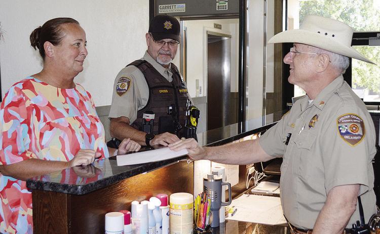 From left, 1st Deputy Court Clerk Kyla Garibay, checks in with Lt. Kenneth Cross, and Sgt. Louis Flowers Thursday at the Custer County Courthouse in Arapaho. CDN | Christian Jacobsen