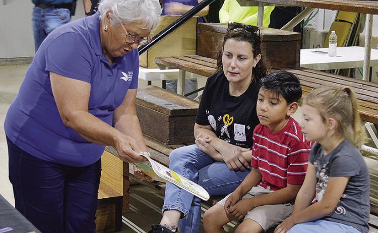 From left, Paula Sawatzky of the Women’s Leadership Committee helps inform WOCS kindergarten teacher Danyal Walters along with students Abdiel Botello and Avery Nickel where their food from their lunchboxes and school meals come from Friday morning at the Custer County Free Fair. CDN | Christian Jacobsen