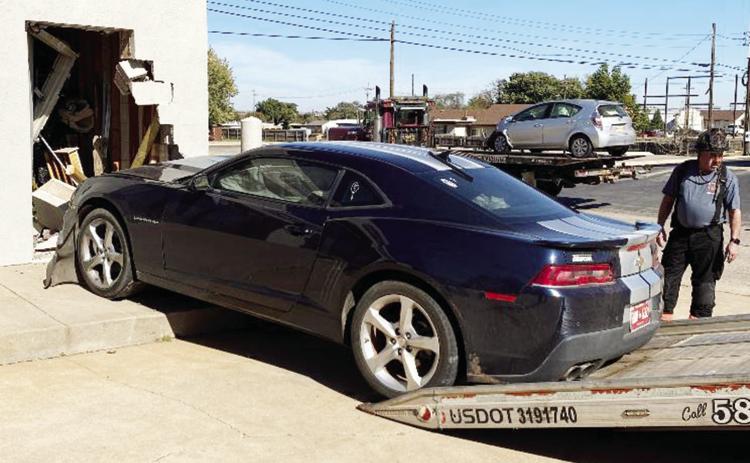 Clinton Fireman John Denney watches as this Camaro is loaded on the wrecker’s trailer Tuesday afternoon after a two-vehicle crash caused the vehicle to run into Dupree’s Flowers &amp; Gifts located at Gary Boulevard and Seventh Street. The other vehic