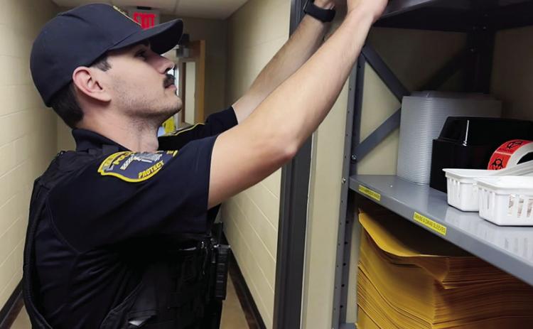 Ofc. Brady Bridges retrieves an evidence box while preparing to file a report at the Clinton Police Department. CDN | Shiann Dawson