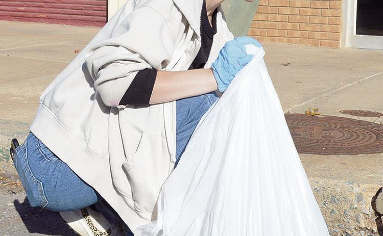 Senior Brylee Jones picks up trash left in the street as part of her Capstone community service on Frisco Avenue. CDN | Micah Ashcraft