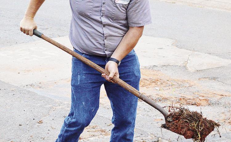 Donavan Phipps shovels debris away after clearing asphalt from a pipe under the road near the 1800 block of Opal Avenue. CDN | Micah Ashcraft
