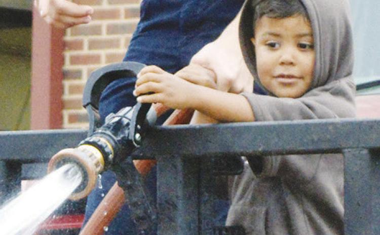 Firefighter Colten Helms, left, shows Isaiah Ford how to use and aim a firehose during the Cheyenne and Arapaho Head Start field trip at the Clinton Fire Department. CDN | Christian Jacobsen