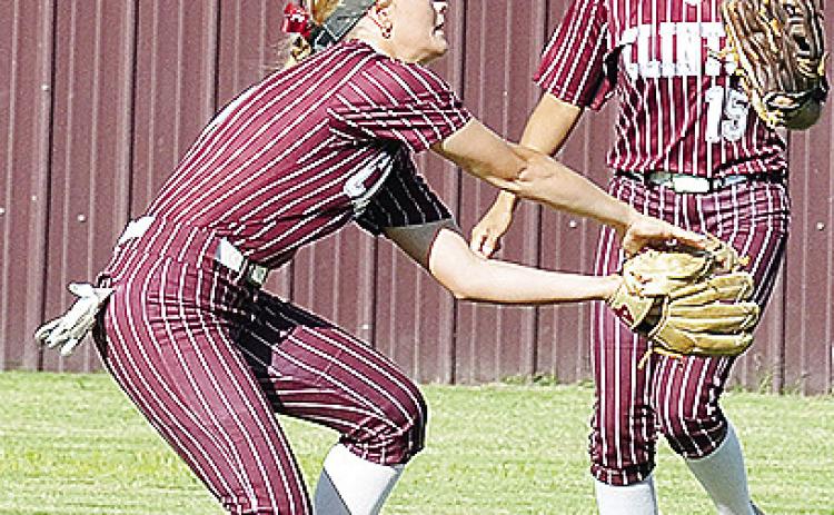 Clinton’s Stella Meacham, left, secures the ball in her glove with No. 15 Audrina Trout coming over for back up during the Lady Reds’ game against Bishop McGuiness. CDN | Sam Goodwyn