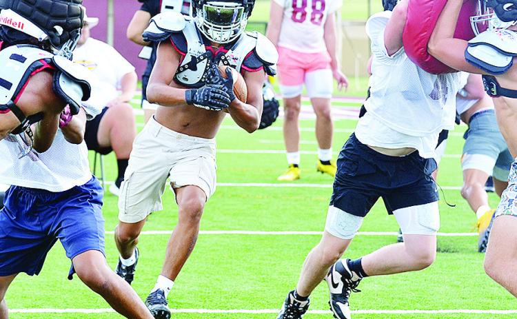 Clinton’s Jesus Gutierrez carries the ball between two blocks set by CJ Begay on DJ Lister, left, and Zaryk Baker on Vince Jones during preseason practice at the Tornado Bowl. CDN | Sam Goodwyn