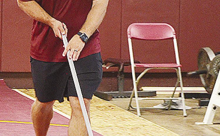 New Clinton High School wrestling coach Rhett Blundell sweeps the mats in the high school wrestling room Monday. CDN | Sam Goodwyn
