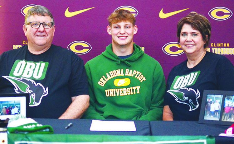 Clinton’s Wyatt Willoughby, center, celebrates Friday with his father Rodney, left, and mother April, right, after signing to throw for Oklahoma Baptist University’s track and field team next year. CDN | Sam Goodwyn