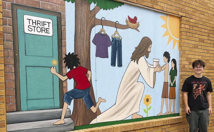 Micah Segler stands by the mural he designed and his fellow CHS art classmates painted outside the Twice is Nice thrift store at 113 S. 7th St. CDN | Courtesy photo