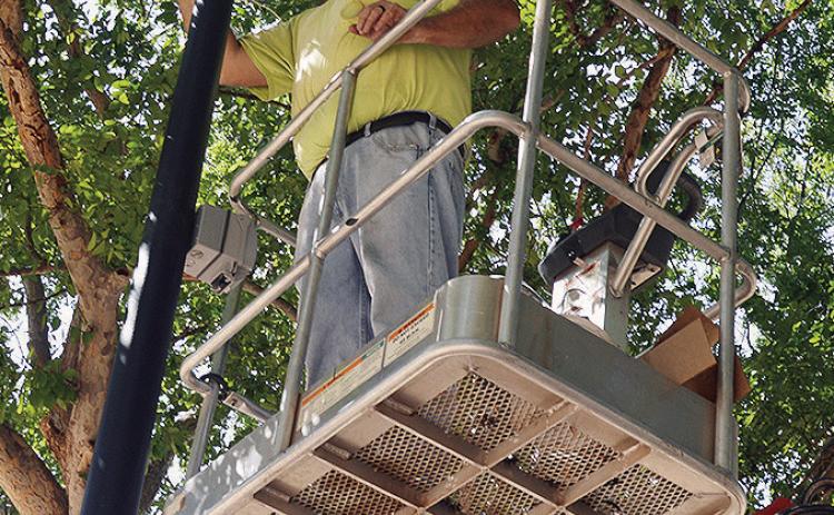 Chuck Fischer of Williams Electric helps install new lights Thursday at the McLain Rogers Park Amphitheater in anticipation of “Oklahoma!” being performed at the venue. CDN | Christian Jacobsen
