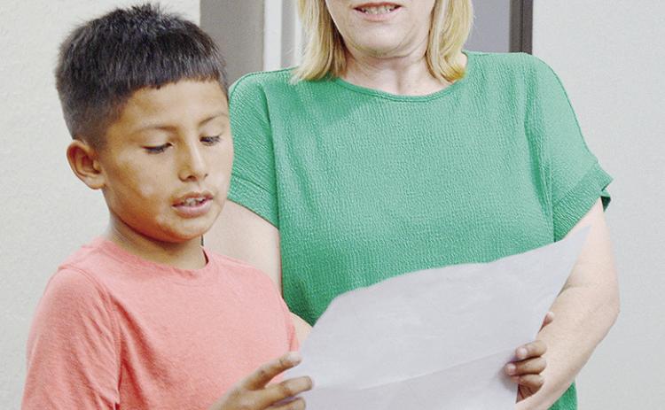 Fourth-grader Jarrod Moss, left, presents a book report to the Clinton Public Schools Board of Education, alongside Southwest Elementary School Librarian Christy Stephens. CDN | Micah Ashcraft