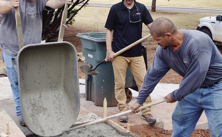 From left, James Holden, Parks Supt. Lyndon Perry, and Robert Plaza pour and level new concrete slabs for wheelchair access and usage Friday morning at the McLain Rogers Park Amphitheater. CDN | Christian Jacobsen
