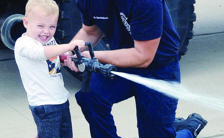 Daxton Hobbs, left, shows the power of his fire hose, as he shoots traffic cones with the help of Lt. Billy Gerstenkorn during the Cheyenne and Arapaho Head Start field trip at the Clinton Fire Department. CDN | Christian Jacobsen