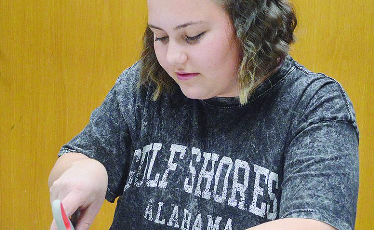 Karleigh James cuts out scraps from an old magazine to put on her 2026 vision board during an activity Monday evening at the Clinton Public Library. CDN | Micah Ashcraft