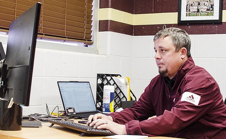 New Clinton football coach Trevor Powers works on his computer Monday as he settles into his new office. CDN | Sam Goodwyn