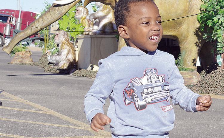 Jeremiah Gathings runs as he enjoys the animatronic animals with the Wild Adventures Smart Zoo experience hosted Thursday afternoon at the Sutherlands parking lot. CDN | Micah Ashcraft