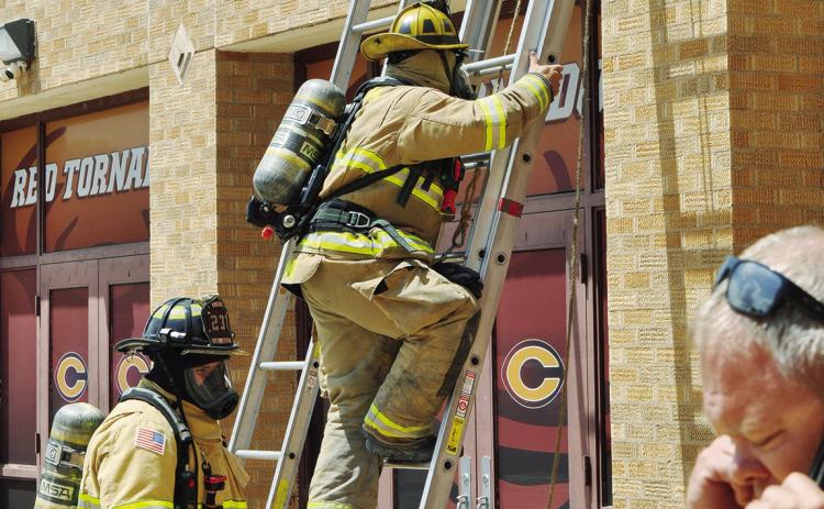 Ascending the ladder to check out the roof of the Clinton Middle School Cafeteria are firemen Austin Long and Lt. Joe Williams, as CMS Principal Gene Ray talks on the phone Monday afternoon. CDN | Staff Photo